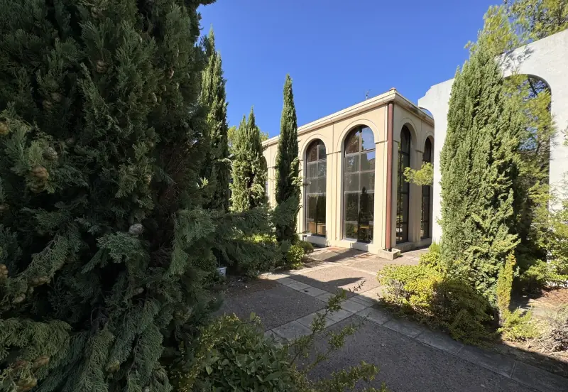 Le bâtiment à arcades entre les cyprès