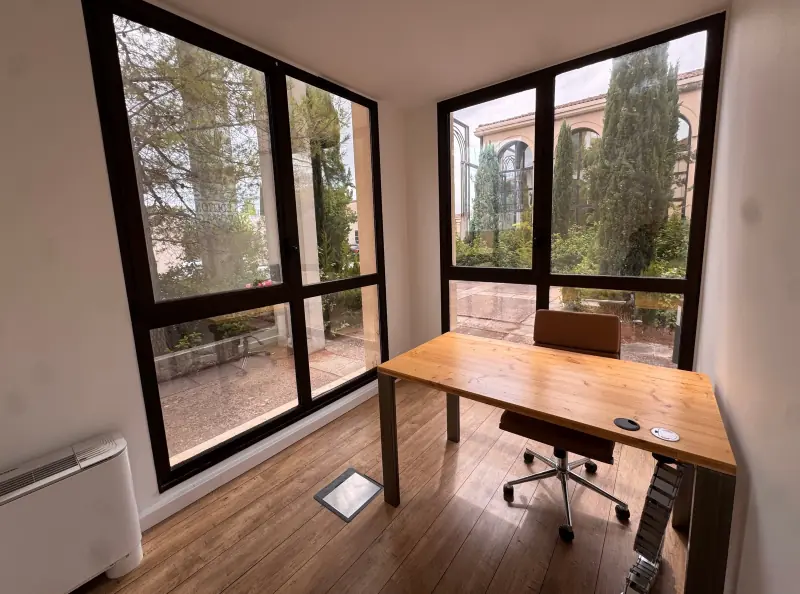 Bureau d’angle avec deux grandes baies sur les cyprès et le bâtiment à arcades