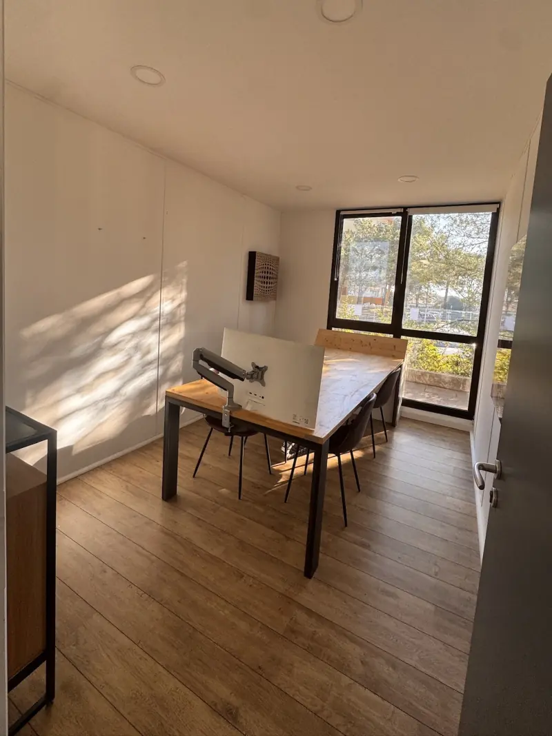 Bureau fermé avec ombres de feuillage au mur et baie vitrée
