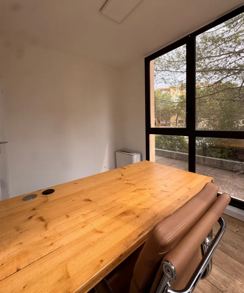 Table en bois et fauteuil camel devant la baie vitrée