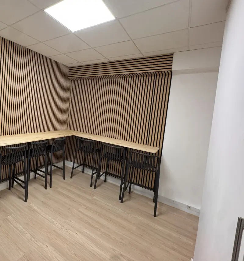 Coin repas, comptoir en bois en L, tabourets noirs et mur en tasseaux