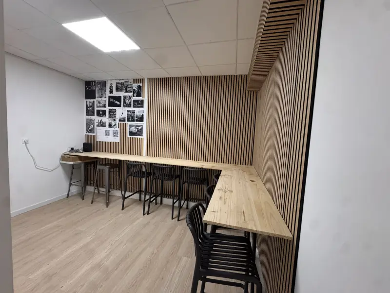 Coin repas du bâtiment E2 : comptoir en bois clair et tabourets noirs