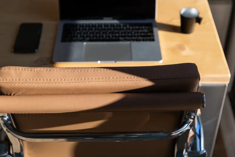Dossier du fauteuil en cuir camel devant un MacBook