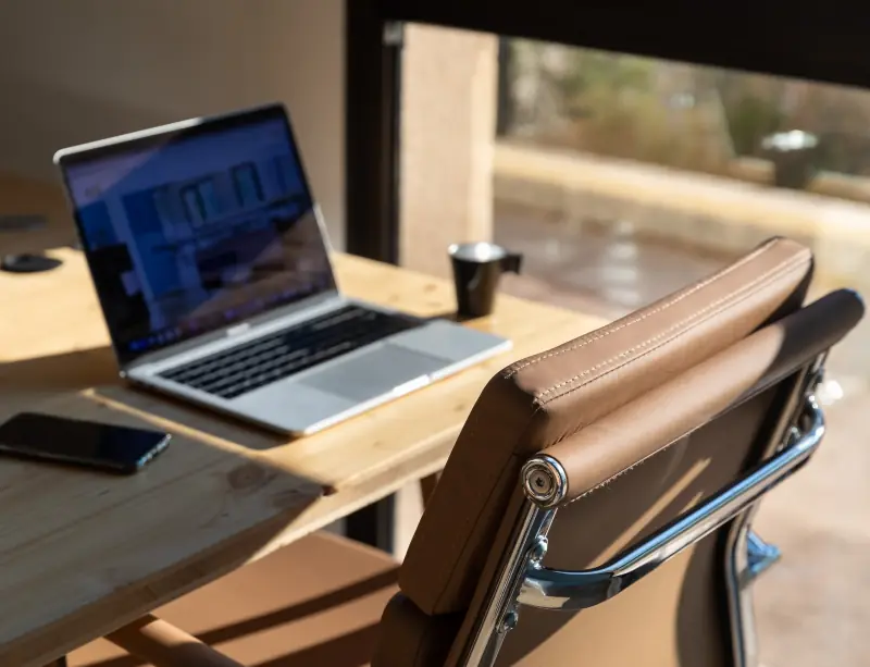 Poste de travail au soleil, fauteuil en cuir et ordinateur portable