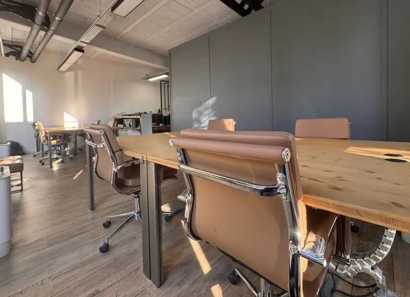 L’open space au soleil, grande table en bois massif et fauteuils en cuir camel au premier plan