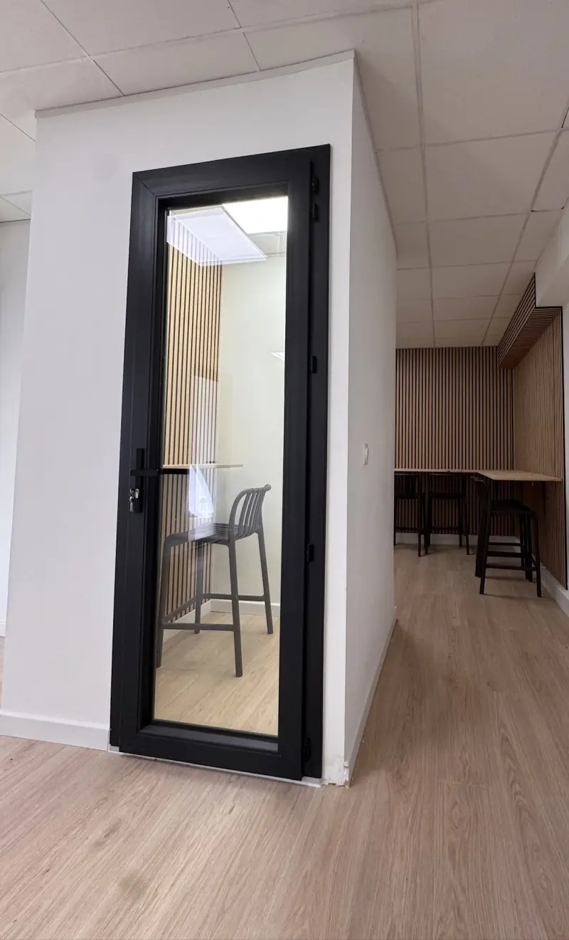 La phone box du bâtiment E2, porte vitrée noire et tabouret