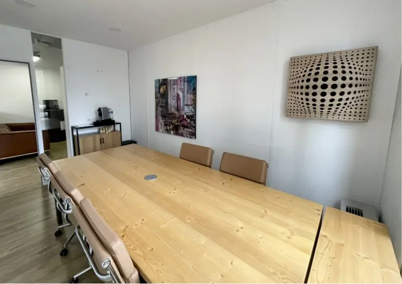Salle de réunion avec panneau acoustique en bois perforé et fauteuils en cuir